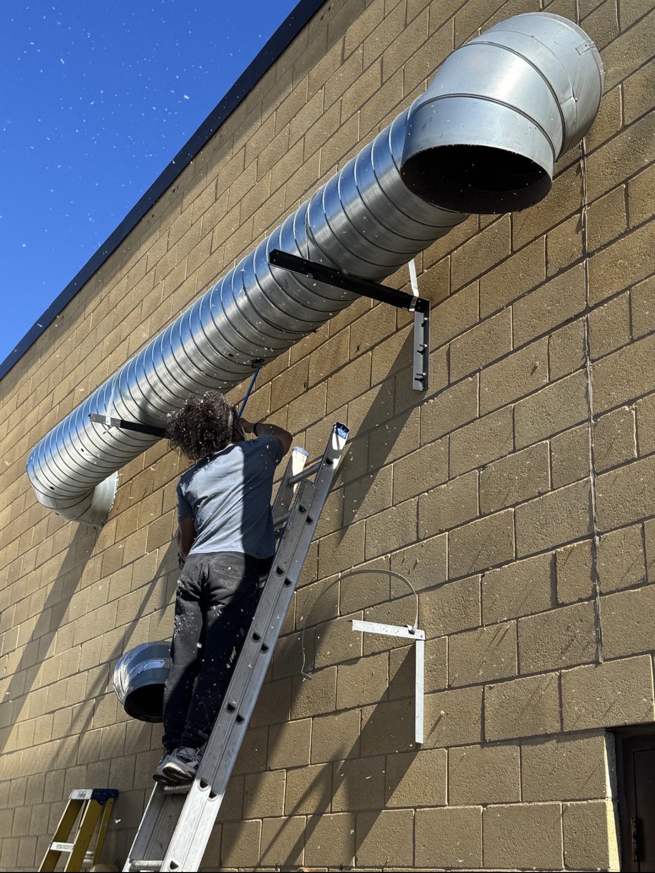 Technician cleaning large commercial exterior duct