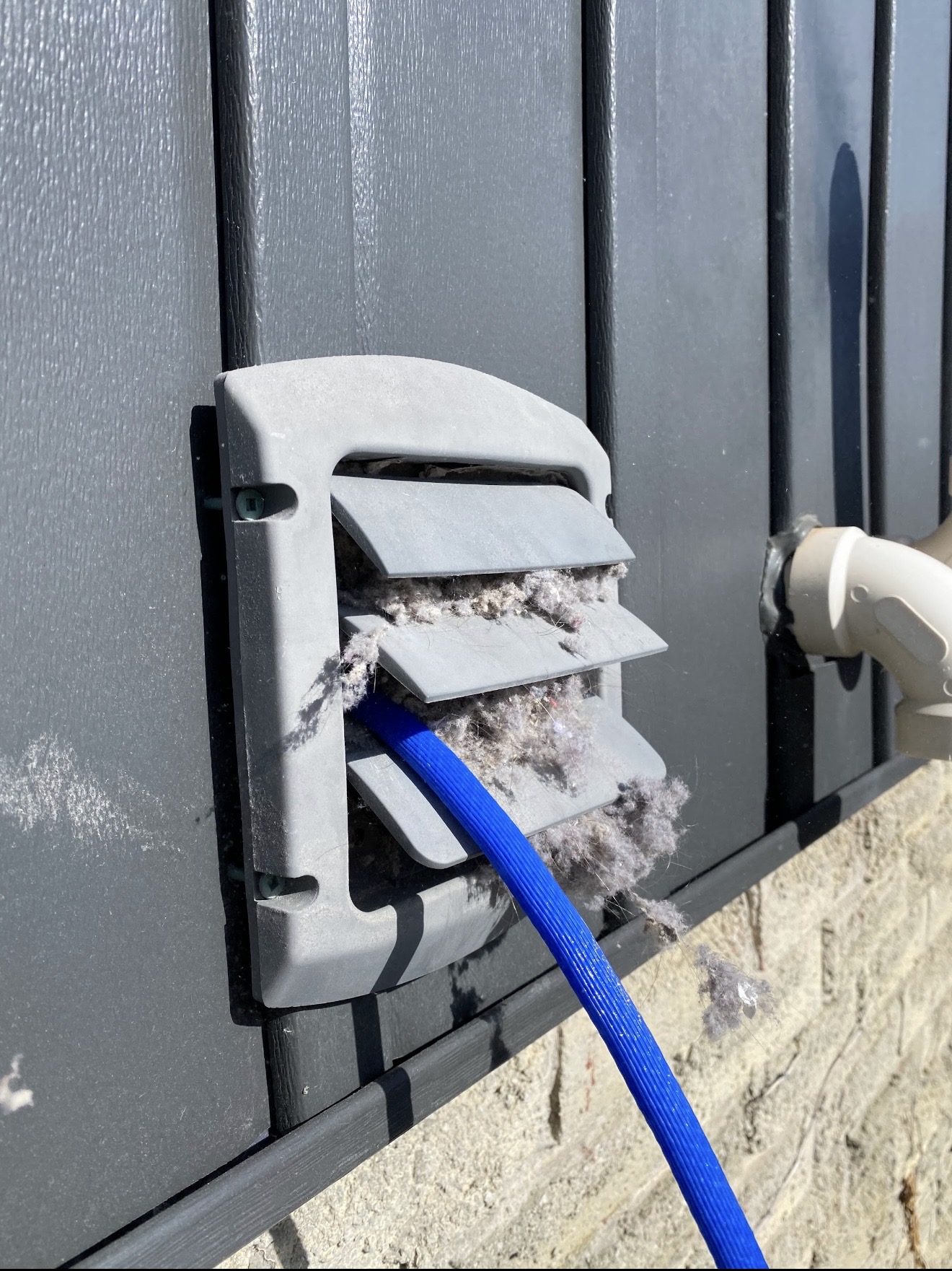 Lint buildup being cleared from an exterior dryer vent