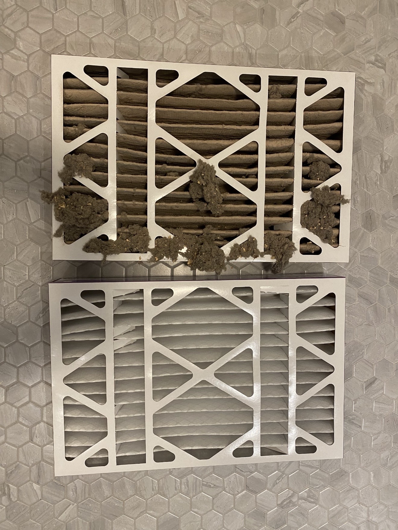 Used dirty furnace filter next to a brand new clean filter